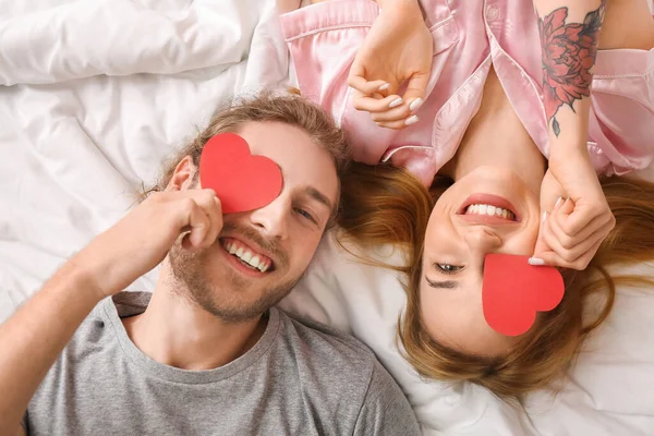 Yatakta Yatan Kırmızı Kalpli Genç Bir Çift Sevgililer Günü Kutlaması — Stok fotoğraf