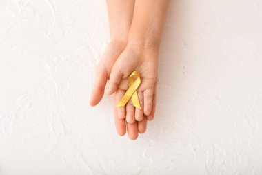 Beyaz arka planda altın kurdeleli eller. Çocukluk kanseri farkındalığı