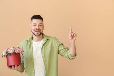 Bir buket güzel çiçekli yakışıklı adam renk arkaplanını işaret ediyor.