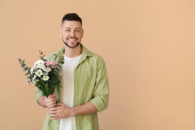 Renkli arka planda bir buket güzel çiçekli yakışıklı adam.