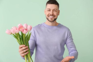 Renkli arka planda bir buket güzel çiçekli yakışıklı adam.