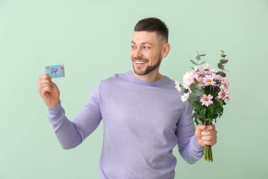 Güzel çiçekleri olan yakışıklı bir adam ve renkli bir hediye kartı.