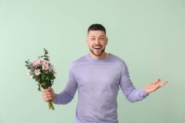Renkli arka planda bir buket güzel çiçekli yakışıklı adam.