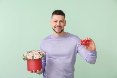 Güzel çiçekleri olan yakışıklı bir adam ve renkli bir hediye kartı.