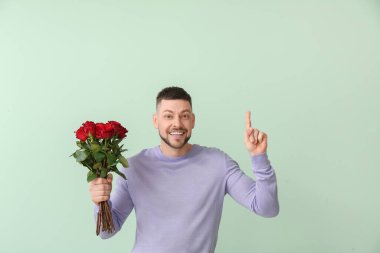 Bir buket güzel çiçekli yakışıklı adam renk arkaplanını işaret ediyor.