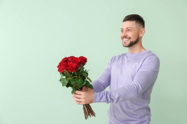 Renkli arka planda bir buket güzel çiçekli yakışıklı adam.