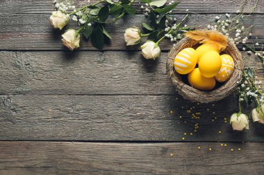 Ahşap arka planda güzel Paskalya yumurtaları ve çiçekleri olan kompozisyon