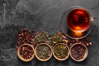 Fincanlı kompozisyon ve koyu arkaplanda kuru çay yaprakları