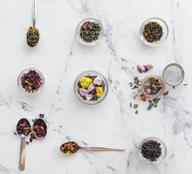 Kuru çay yaprakları ve hafif arkaplanda çiçekler olan kompozisyon