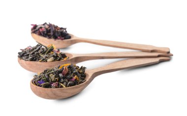 Tahta kaşıklar, kuru çay yaprakları ve beyaz arka planda çiçekler.