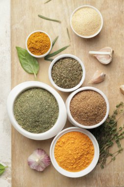 Açık arkaplanda farklı baharat ve bitkiler bulunan tahta