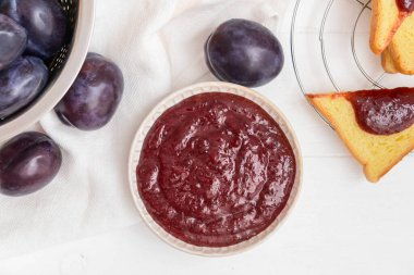 Ahşap zemin üzerinde ev yapımı erik reçeli olan bir kase.