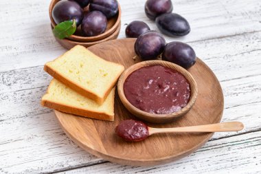 Ahşap zemin üzerinde ev yapımı erik reçeli olan bir kase.