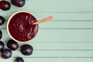 Ahşap zemin üzerinde ev yapımı erik reçeli olan bir kase.