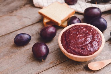 Ahşap zemin üzerinde ev yapımı erik reçeli olan bir kase.