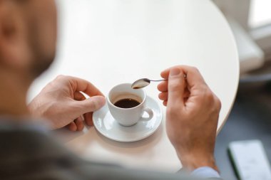 Yakışıklı adam kafede sıcak espresso içiyor.