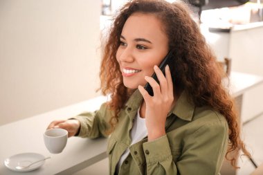 Kafede cep telefonu ve bir fincan sıcak espresso ile güzel bir kadın.