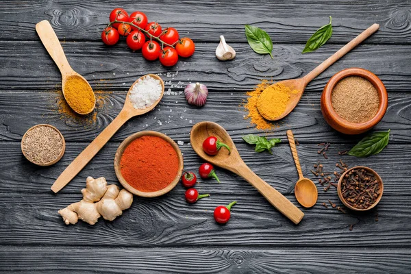 Koyu ahşap arka planda farklı baharat ve sebzelerle kompozisyon