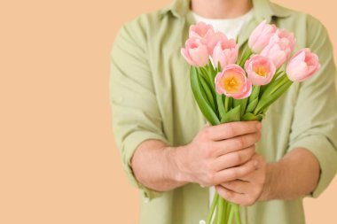 Renkli arka planda bir buket güzel çiçekli yakışıklı adam.