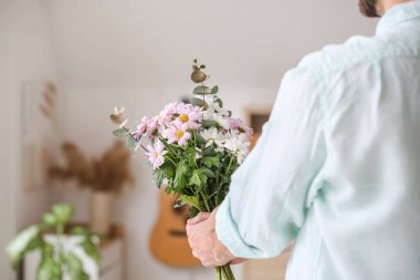 Evinde güzel çiçekleri olan yakışıklı bir adam.