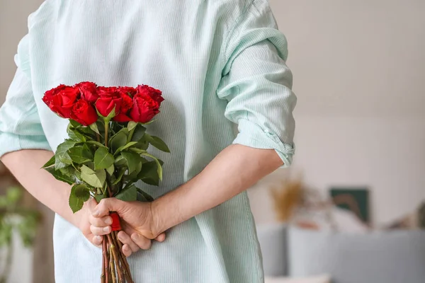 Evinde arkasında bir buket güzel çiçekle yakışıklı bir adam.