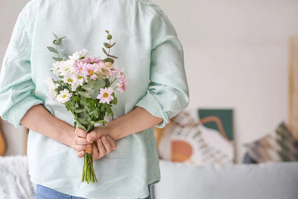Evinde arkasında bir buket güzel çiçekle yakışıklı bir adam.