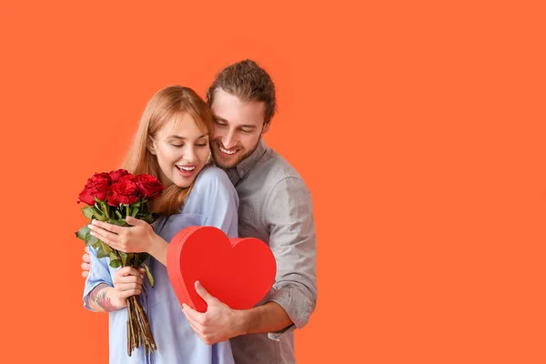 Junges Paar Mit Blumen Und Geschenk Auf Farbigem Hintergrund Valentinstag — Stockfoto