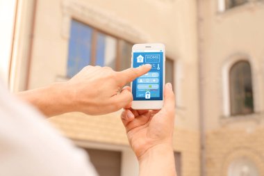 Evin yakınında akıllı ev otomasyonu uygulayan bir adam.