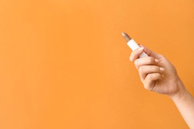 Arka planda doğal dudak merhemi olan bir kadın eli.