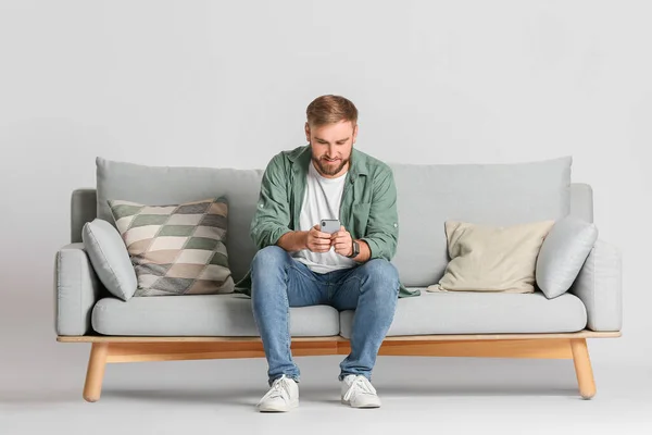 Young Man Mobile Phone Sofa Light Background — Stock Photo, Image