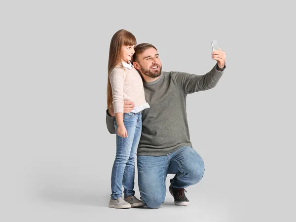 Apa Lánya Szelfit Készít Mobiltelefonnal Könnyű Háttérrel — Stock Fotó