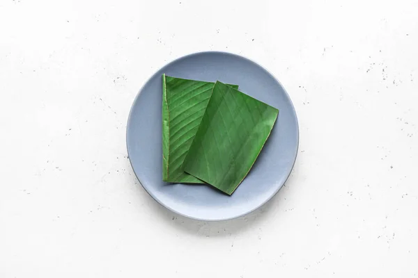 Plate with cut banana leaf on white background