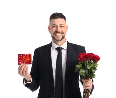 Beyaz arka planda hediye kartı ve çiçekleri olan yakışıklı bir adam.