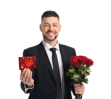 Beyaz arka planda hediye kartı ve çiçekleri olan yakışıklı bir adam.