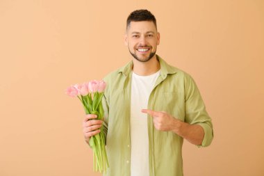 Renkli arka planda bir buket güzel çiçekli yakışıklı adam.