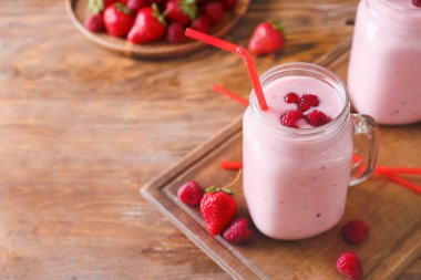 Ahşap arka planda çilekli ve ahududulu bir kavanoz lezzetli smoothie.
