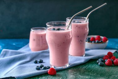 Arkaplanda yabanmersini ve ahududu aromalı bir bardak lezzetli smoothie.