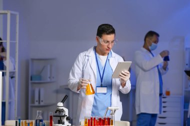 Erkek bilim adamı laboratuarda numuneyle çalışıyor.