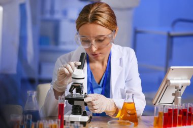Laboratuvarda mikroskopla çalışan kadın bilim adamı.