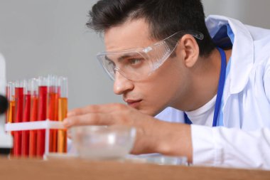 Erkek bilim adamı laboratuarda numunelerle çalışıyor, yakın plan.
