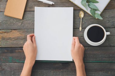 Boş şarjörlü kadın elleri ve tahta arka planda bir fincan kahve.