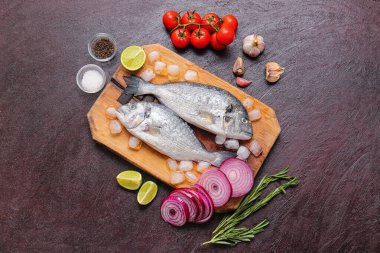 Koyu arkaplanda malzemeli çiğ dorado balığı.