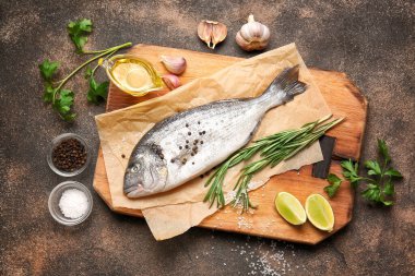 Çiğ dorado balığı, arkaplanda malzemeler var.