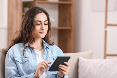 Evde e-kitap okuyan güzel genç bir kadın.
