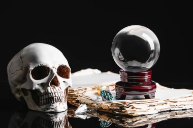 Kristal falcı, insan kafatası ve karanlık arka plan üzerine eski bir kitap.