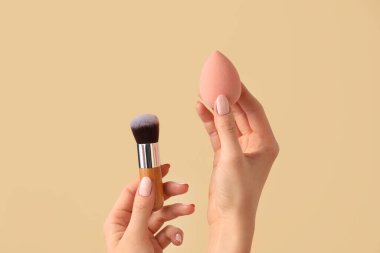 Makyaj süngeri ve renk arkaplan fırçası olan eller