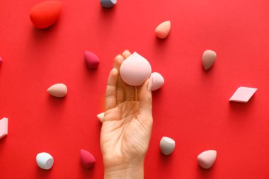 Renkli arka planda makyaj süngeri olan el