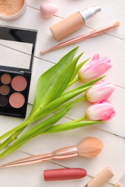 Beyaz ahşap arka planda kozmetik ve bahar çiçekleri