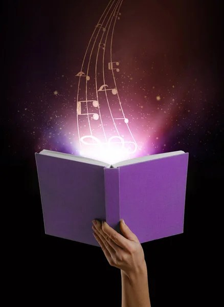 Female Hand Holding Open Book Flying Music Notes Dark Background — Stock Photo, Image