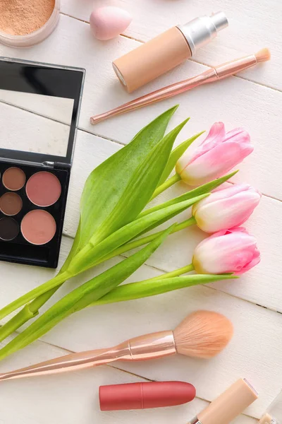 Beyaz ahşap arka planda kozmetik ve bahar çiçekleri